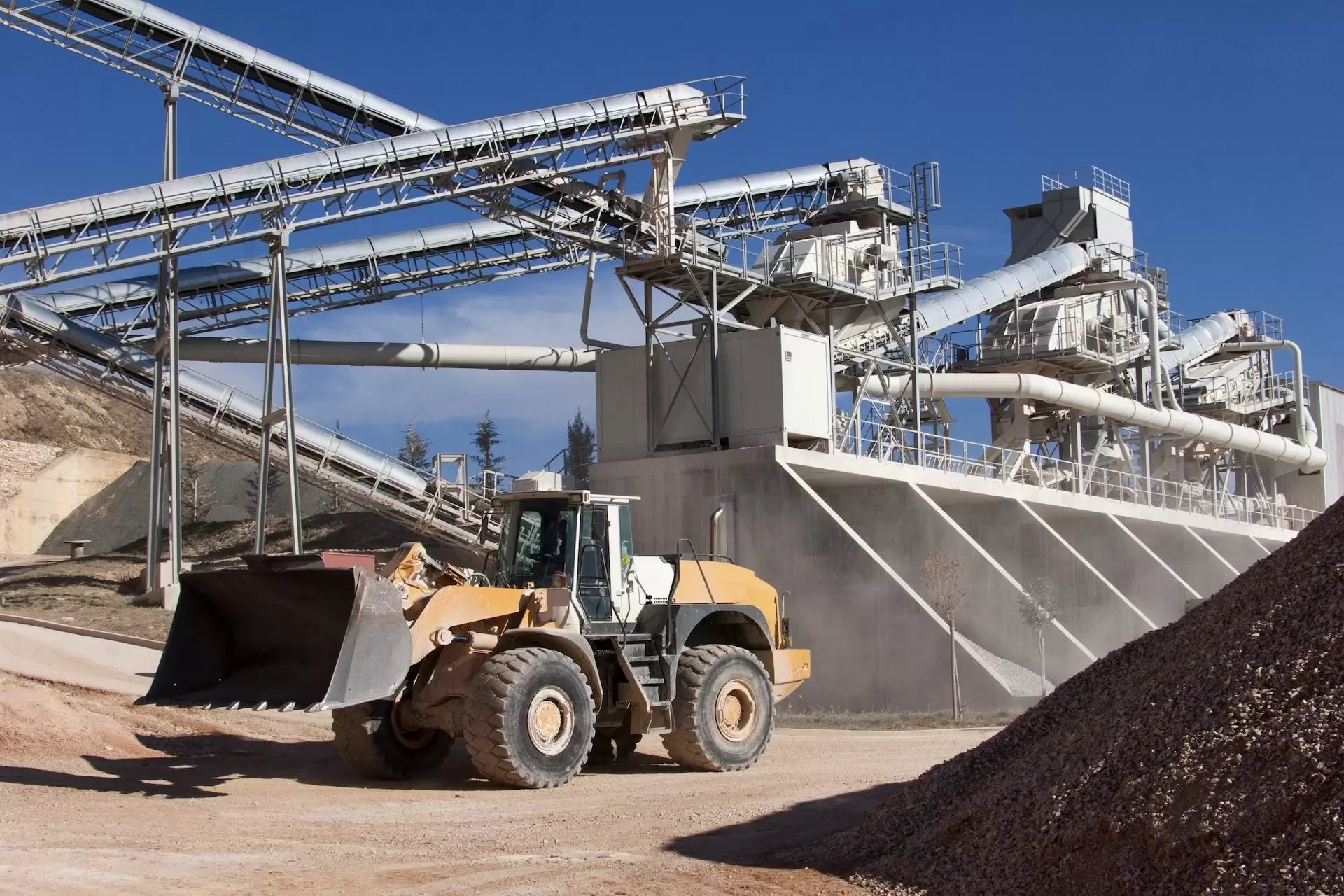 Heavy mining equipment operating in an open-pit extraction site under direct sunlight.